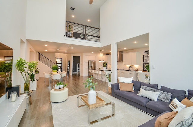 living area with light wood finished floors, visible vents, stairway, and recessed lighting