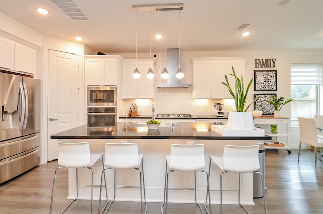 kitchen featuring a center island with sink, appliances with stainless steel finishes, and white cabinets