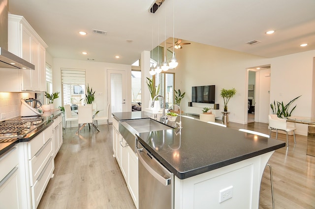 kitchen featuring dark countertops, a spacious island, hanging light fixtures, stainless steel appliances, and white cabinetry