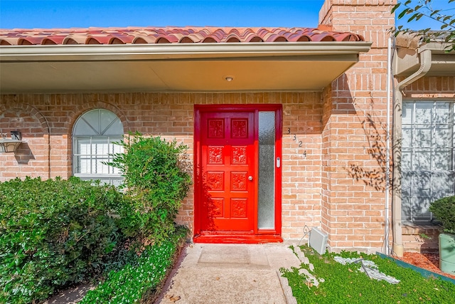 property entrance with a tile roof and brick siding