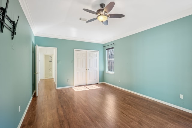 unfurnished bedroom with visible vents, crown molding, baseboards, hardwood / wood-style floors, and a closet