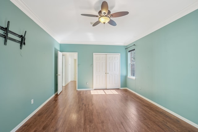 unfurnished bedroom with hardwood / wood-style floors, crown molding, baseboards, and a closet