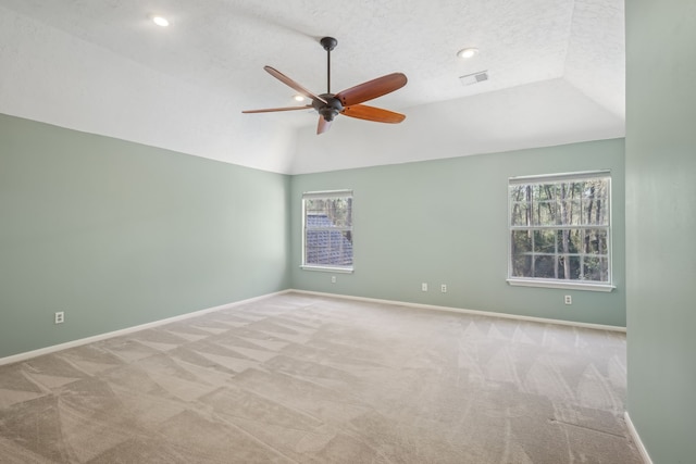 carpeted empty room with a ceiling fan, visible vents, baseboards, vaulted ceiling, and a textured ceiling