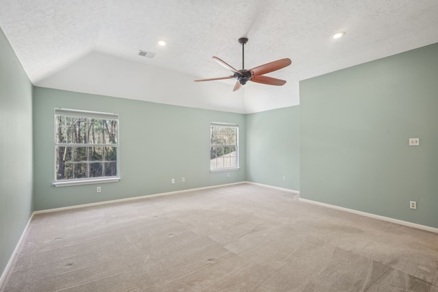 carpeted spare room featuring visible vents, baseboards, ceiling fan, lofted ceiling, and a textured ceiling