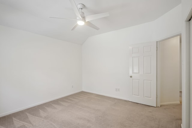 spare room featuring light colored carpet, baseboards, a ceiling fan, and vaulted ceiling