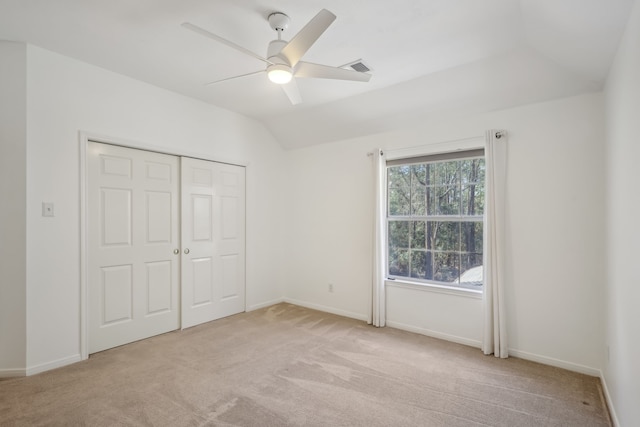 unfurnished bedroom with baseboards, light carpet, a closet, and vaulted ceiling