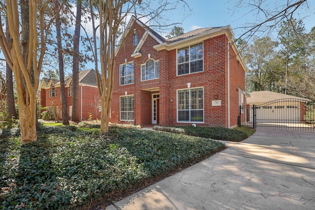 view of front of property with a garage, brick siding, driveway, and a gate