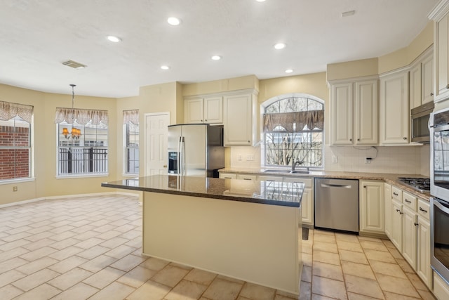 kitchen with visible vents, backsplash, a kitchen island, stainless steel appliances, and a sink