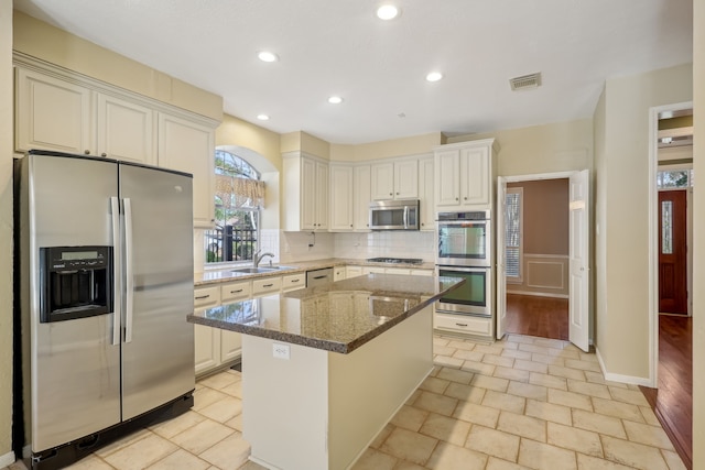 kitchen featuring dark stone countertops, visible vents, decorative backsplash, appliances with stainless steel finishes, and a center island