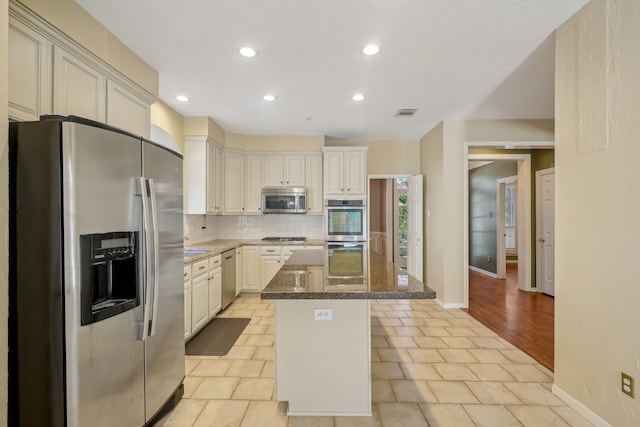 kitchen featuring dark stone countertops, recessed lighting, appliances with stainless steel finishes, tasteful backsplash, and a center island