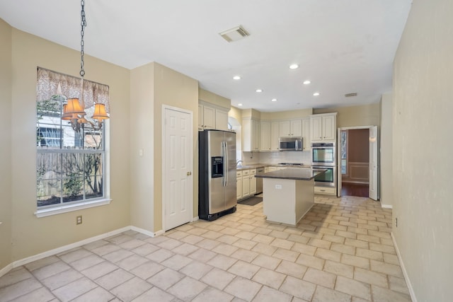 kitchen featuring baseboards, visible vents, decorative backsplash, appliances with stainless steel finishes, and a center island