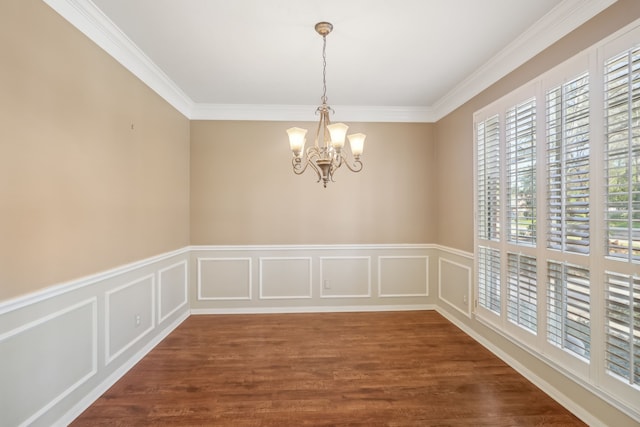 spare room featuring a chandelier, a decorative wall, crown molding, and dark wood-type flooring