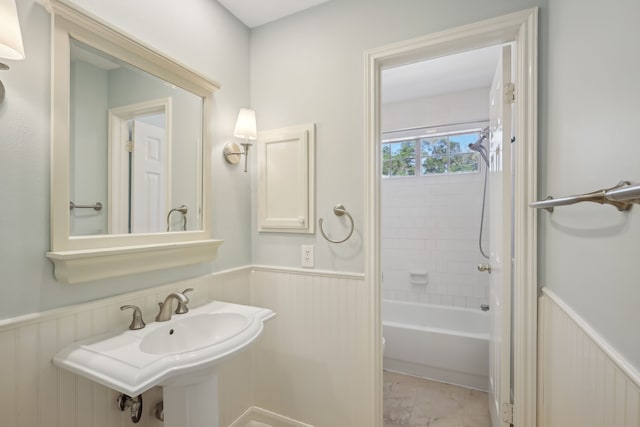 bathroom with bathtub / shower combination, a wainscoted wall, and a sink