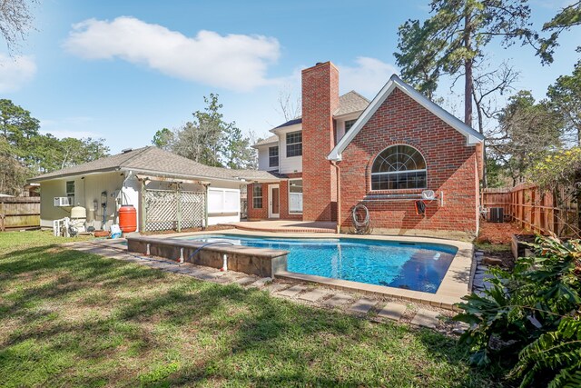 back of house featuring brick siding, central AC, a lawn, a chimney, and a fenced backyard