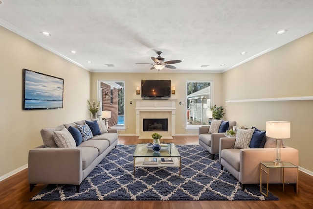 living area with a ceiling fan, a fireplace with flush hearth, wood finished floors, and baseboards