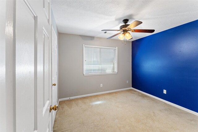 carpeted spare room featuring visible vents, ceiling fan, a textured ceiling, and baseboards