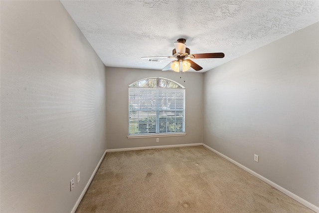 spare room featuring a ceiling fan, baseboards, visible vents, a textured ceiling, and light colored carpet