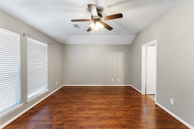 empty room featuring vaulted ceiling, baseboards, visible vents, and wood finished floors