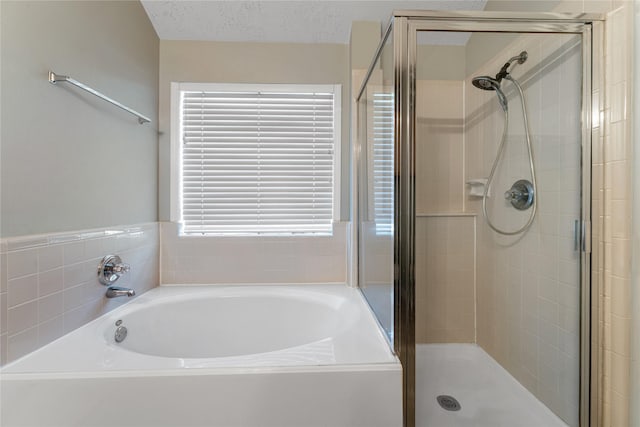 bathroom with a bath, a stall shower, and a textured ceiling