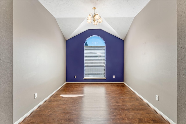 unfurnished room with wood finished floors, baseboards, an inviting chandelier, vaulted ceiling, and a textured ceiling