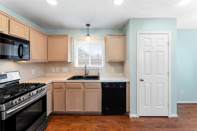 kitchen featuring black appliances, light countertops, light brown cabinetry, and a sink