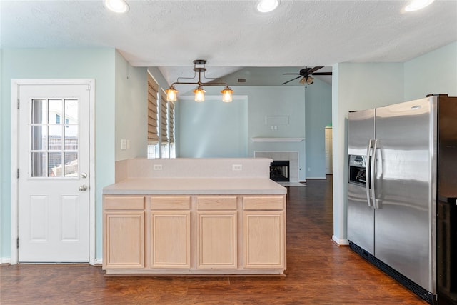 kitchen with dark wood-type flooring, light brown cabinets, stainless steel refrigerator with ice dispenser, a tiled fireplace, and a peninsula