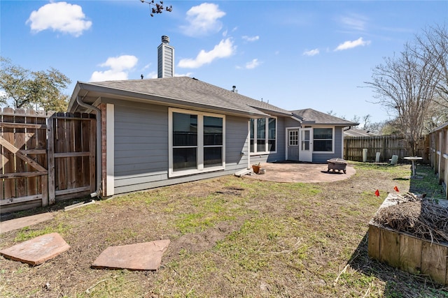 back of house featuring a fenced backyard, a fire pit, a shingled roof, a chimney, and a patio area