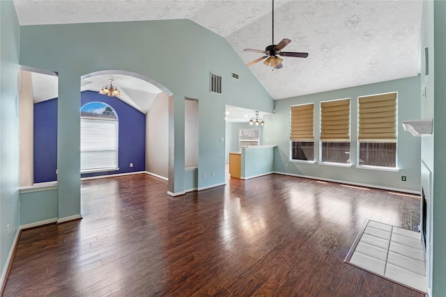 unfurnished living room featuring visible vents, ceiling fan with notable chandelier, arched walkways, a textured ceiling, and wood-type flooring