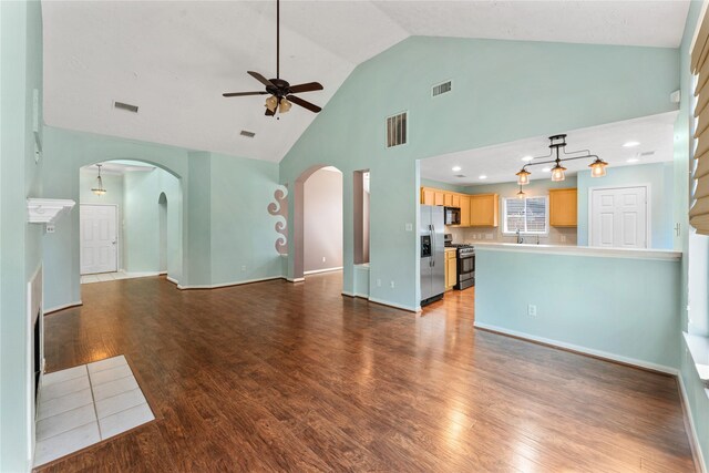 unfurnished living room with wood finished floors, arched walkways, and visible vents