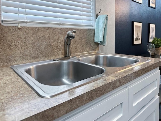 interior details with a hot tub, white cabinets, and a sink
