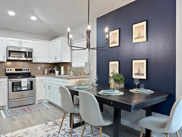 kitchen featuring appliances with stainless steel finishes, white cabinets, backsplash, and pendant lighting