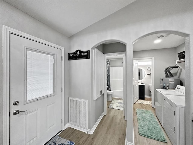 interior space featuring visible vents, washer and clothes dryer, baseboards, and wood finished floors