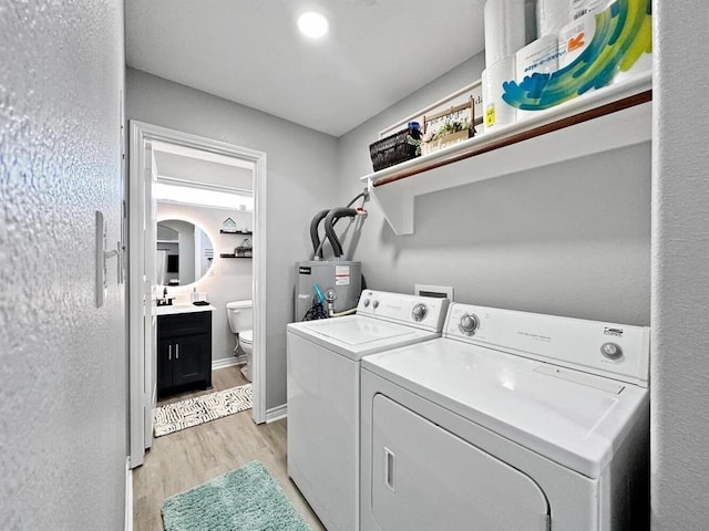 laundry room with arched walkways, laundry area, water heater, light wood-type flooring, and washer and clothes dryer