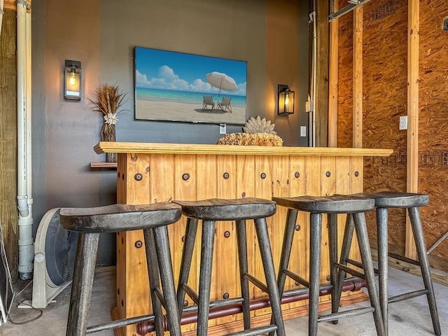 bar with a dry bar and concrete flooring