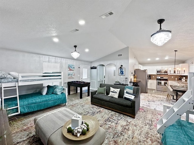 living area featuring a chandelier, arched walkways, wood finished floors, visible vents, and vaulted ceiling
