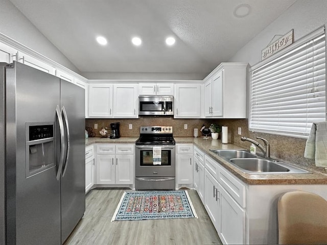 kitchen with white cabinets, appliances with stainless steel finishes, light countertops, and a sink
