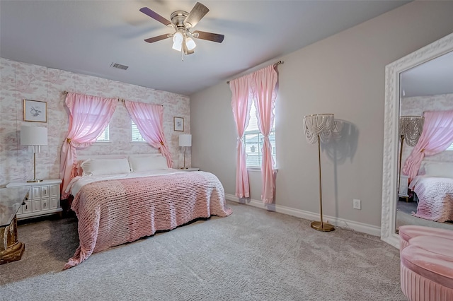 carpeted bedroom with a ceiling fan, visible vents, baseboards, and wallpapered walls