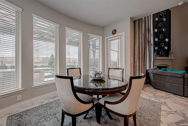 dining area featuring marble finish floor, a fireplace, and baseboards