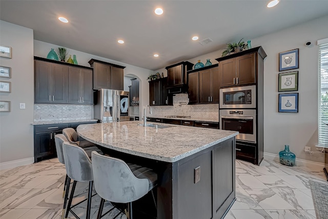 kitchen with marble finish floor, a kitchen island with sink, stainless steel appliances, and a sink