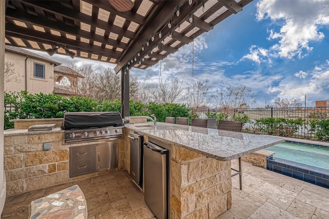 view of patio / terrace with area for grilling, fence, exterior kitchen, a bar, and a pergola