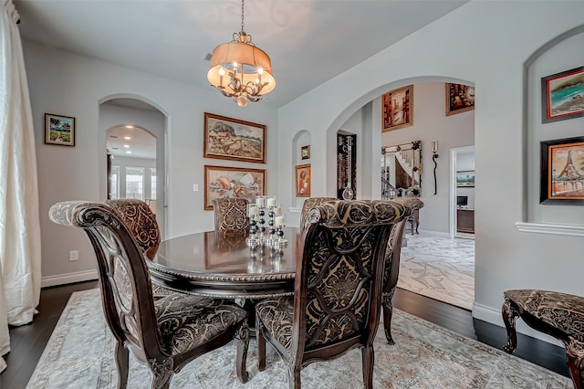 dining area featuring a notable chandelier, baseboards, arched walkways, and wood finished floors