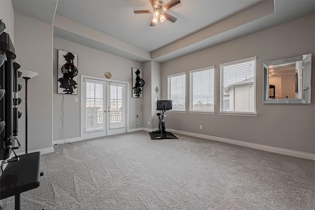 workout area with french doors, light carpet, ceiling fan, and baseboards