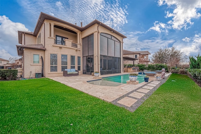 rear view of property featuring a lawn, a balcony, a sunroom, and stucco siding