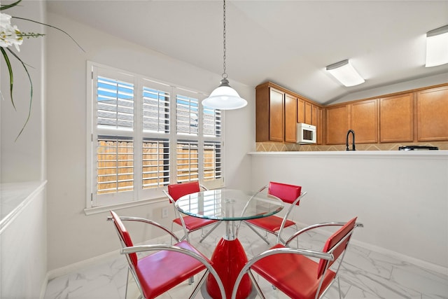 dining space featuring marble finish floor, vaulted ceiling, and baseboards