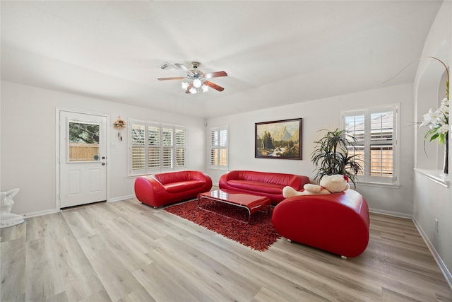 living area featuring light wood-style flooring, baseboards, and a ceiling fan