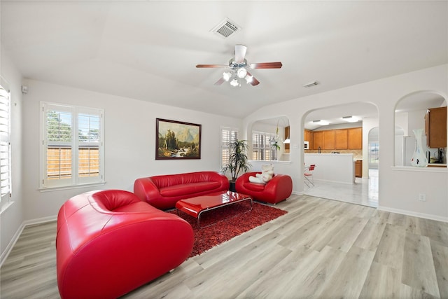 living room with light wood-style floors, lofted ceiling, visible vents, and baseboards