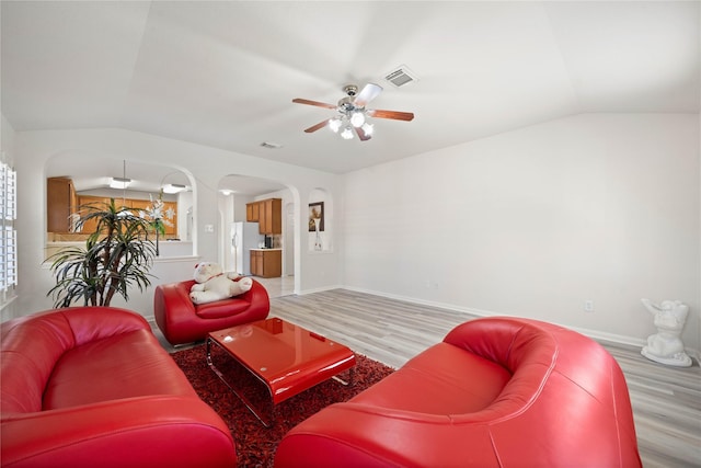 living room featuring vaulted ceiling, arched walkways, wood finished floors, and visible vents