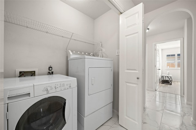 clothes washing area featuring baseboards, marble finish floor, laundry area, and washer and dryer