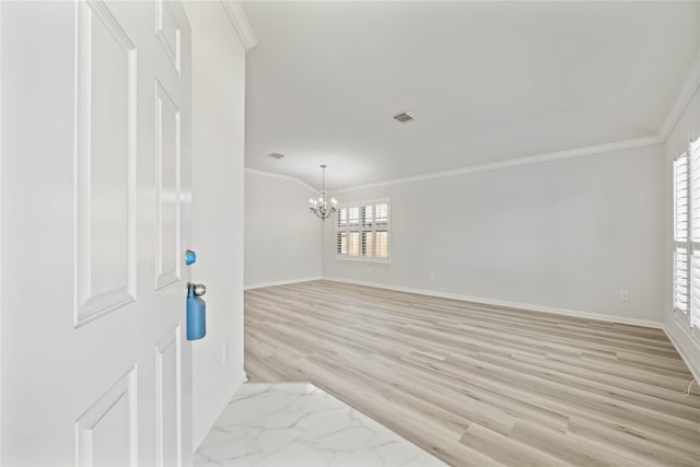 spare room featuring light wood-style floors, a notable chandelier, crown molding, and baseboards