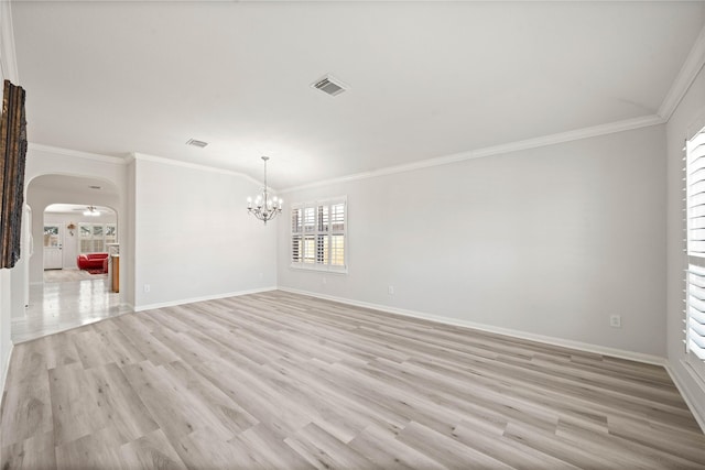 empty room with arched walkways, ornamental molding, light wood-style flooring, and baseboards